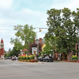 Image of the Queen Street and King Street intersection, with flowering trees and full flower beds along a store-lined street, located just a few doors down from Meritage House.